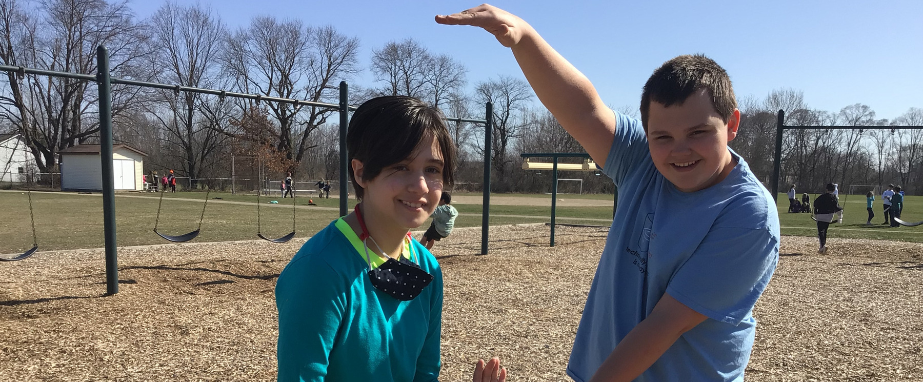 A female student stands to the left as a male student measures her with his hands.