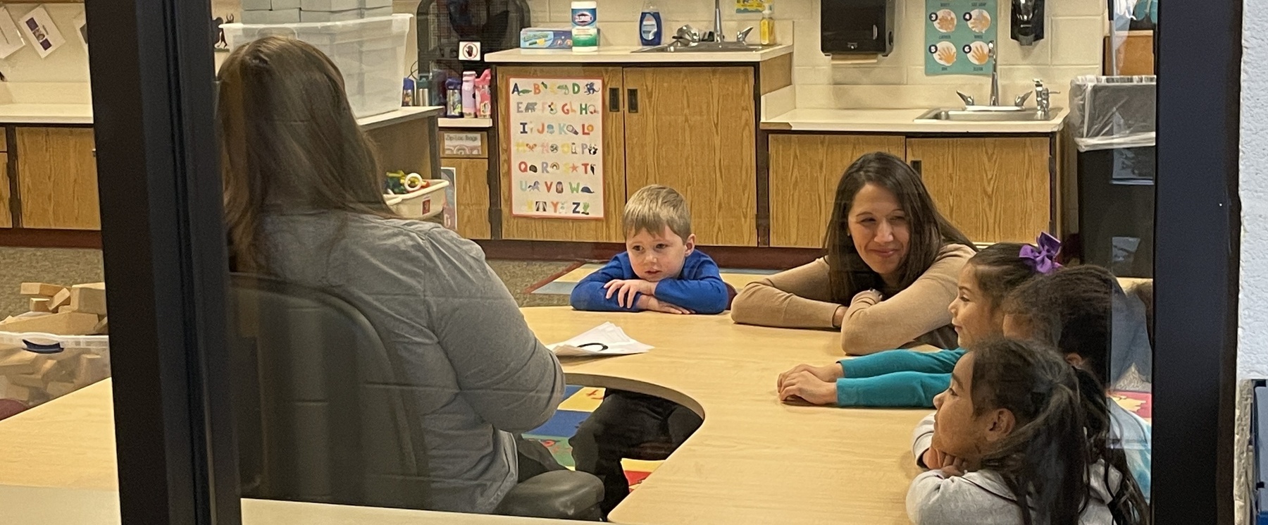 children working with their teachers at a small group table